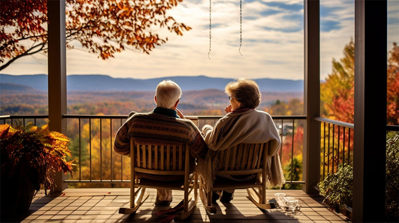 Matrimonio de ancianos mirando la puesta del sol en el porsche de su casa de campo.